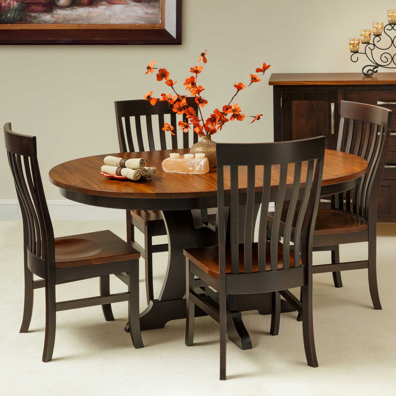 Two-tone round pedestal dining table with a golden oak top and black base plus four dark slat back chairs