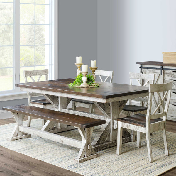 Trestle farm dining table set with candles and greenery, paired with X back chairs and a bench by a window
