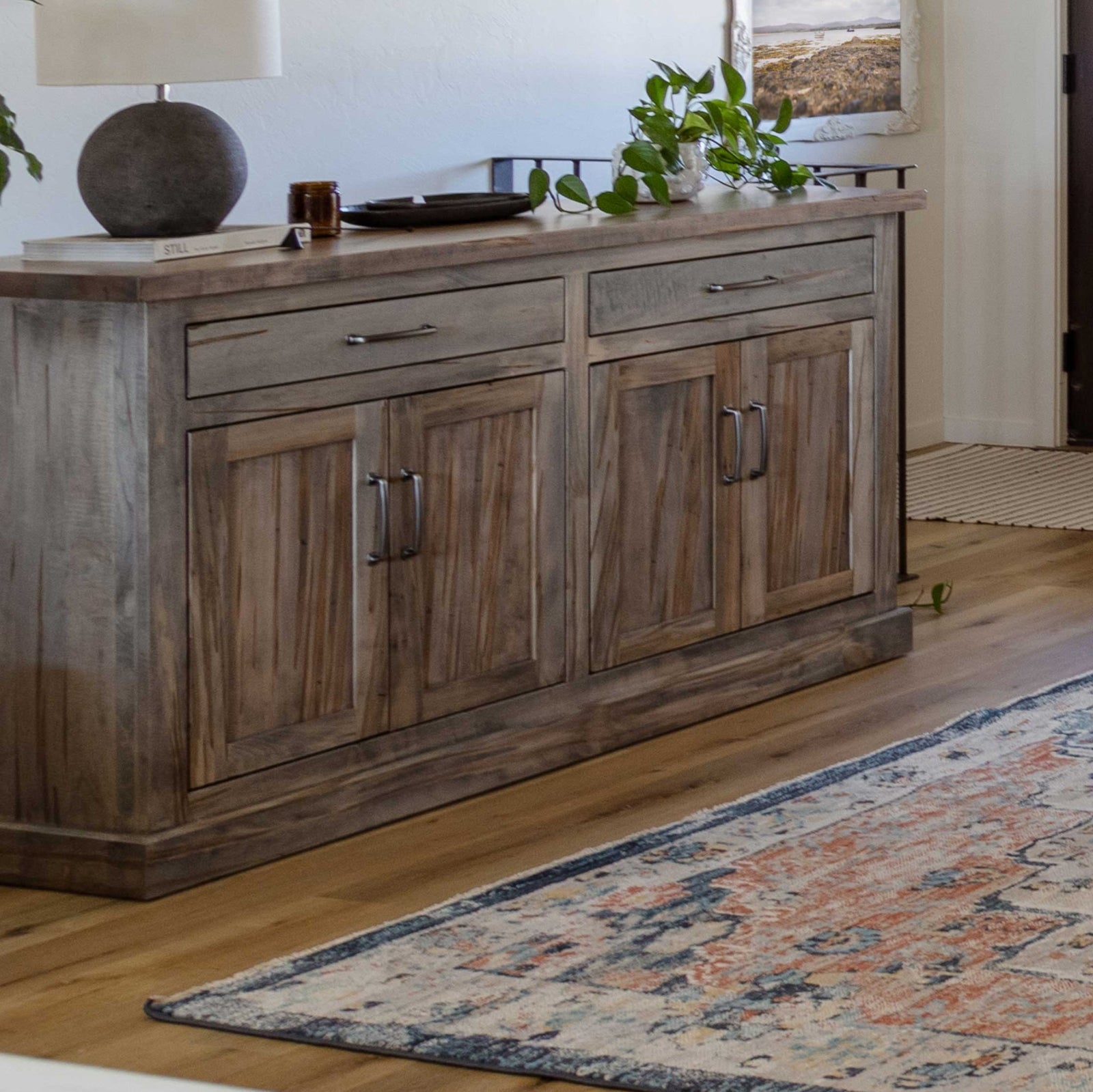 Gray reclaimed wood sideboard buffet with two drawers over four paneled doors, styled with a lamp, tray and trailing plant