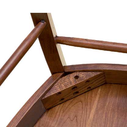 Underside corner detail of a wood bar stool seat showing the leg joint, corner block and doweled pegs