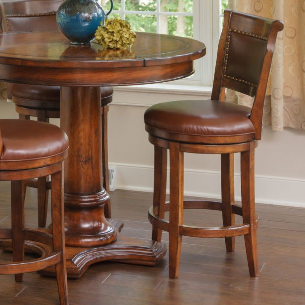 Leather swivel bar stools with nailhead trimmed backs beside a round cherry pub table on dark plank flooring
