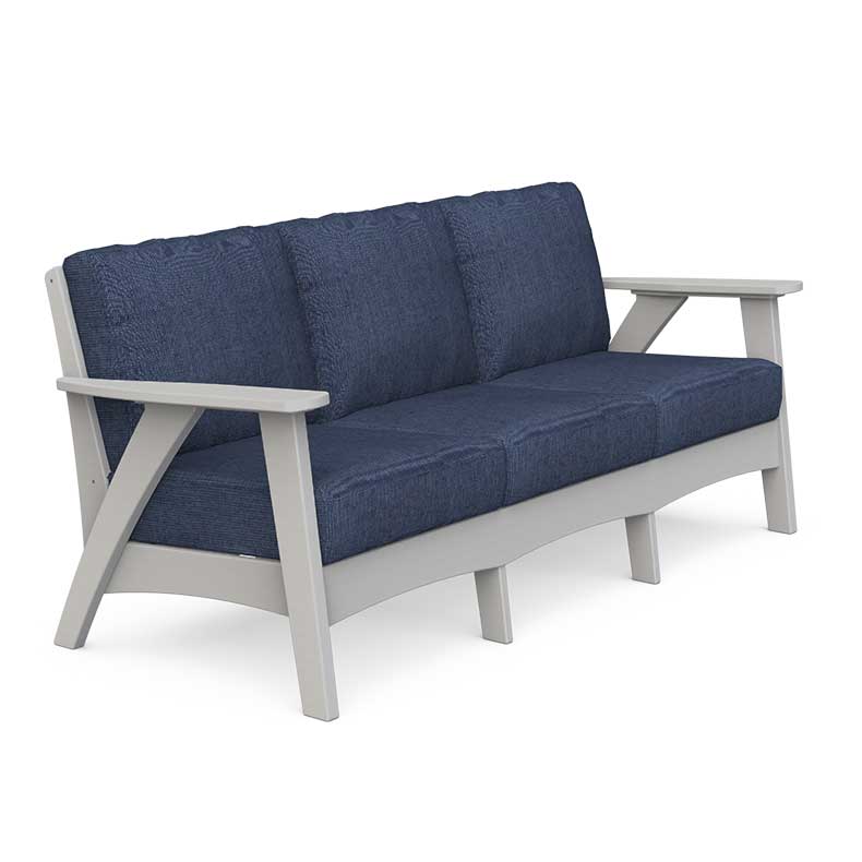 Gray poly outdoor sofa with navy cushions, coffee table and end table styled on a beachfront deck