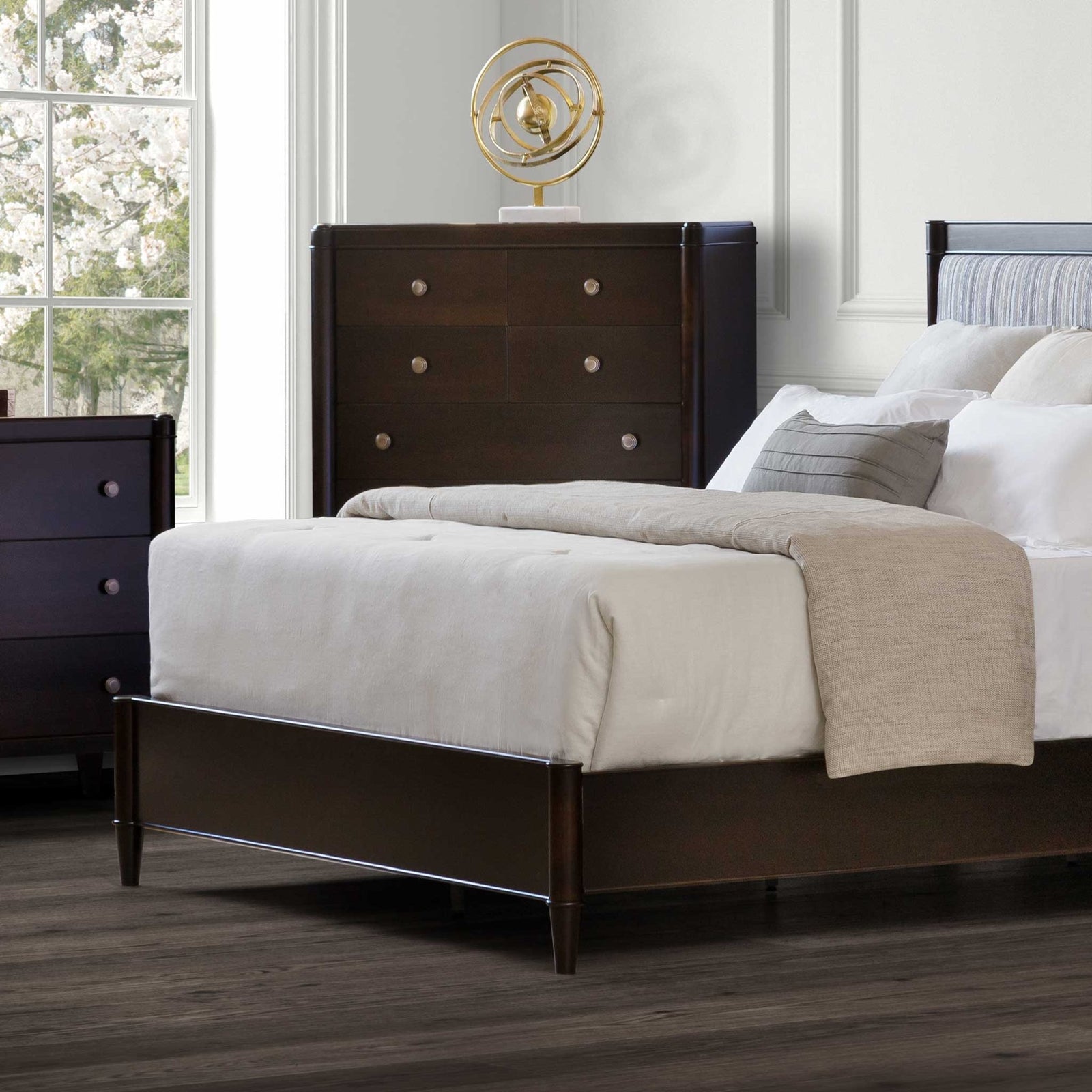 Espresso chest of drawers with eight drawers and round metal knobs beside a bed in a paneled bedroom