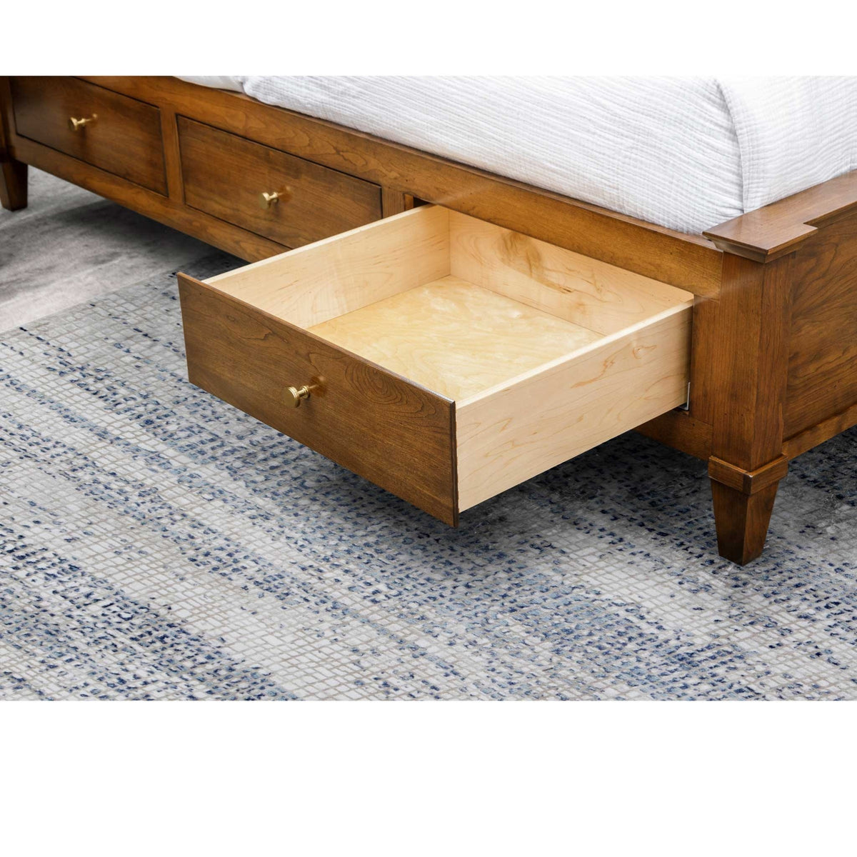 Underbed drawer of the panel storage bed opened to show the deep maple-lined box on smooth glides