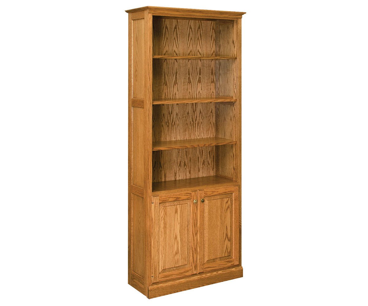 Tall oak bookcase with four open adjustable shelves above two raised panel doors with small brass knobs