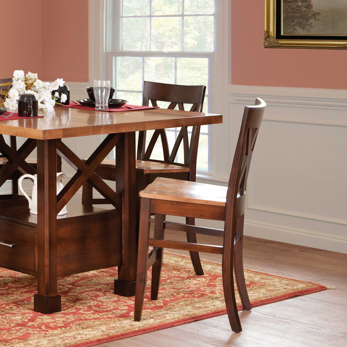 Two dark brown X back counter stools tucked under a two-tone counter height table on a red patterned rug