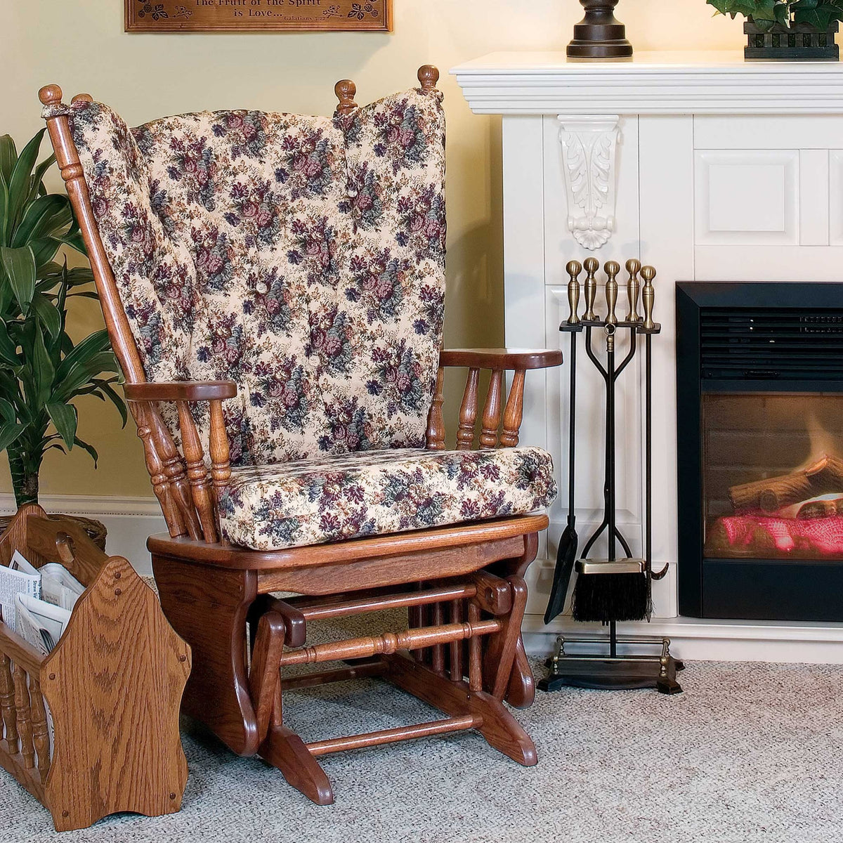 Oak glider rocker with floral cushion set beside a white fireplace mantel and magazine rack in a cozy living room