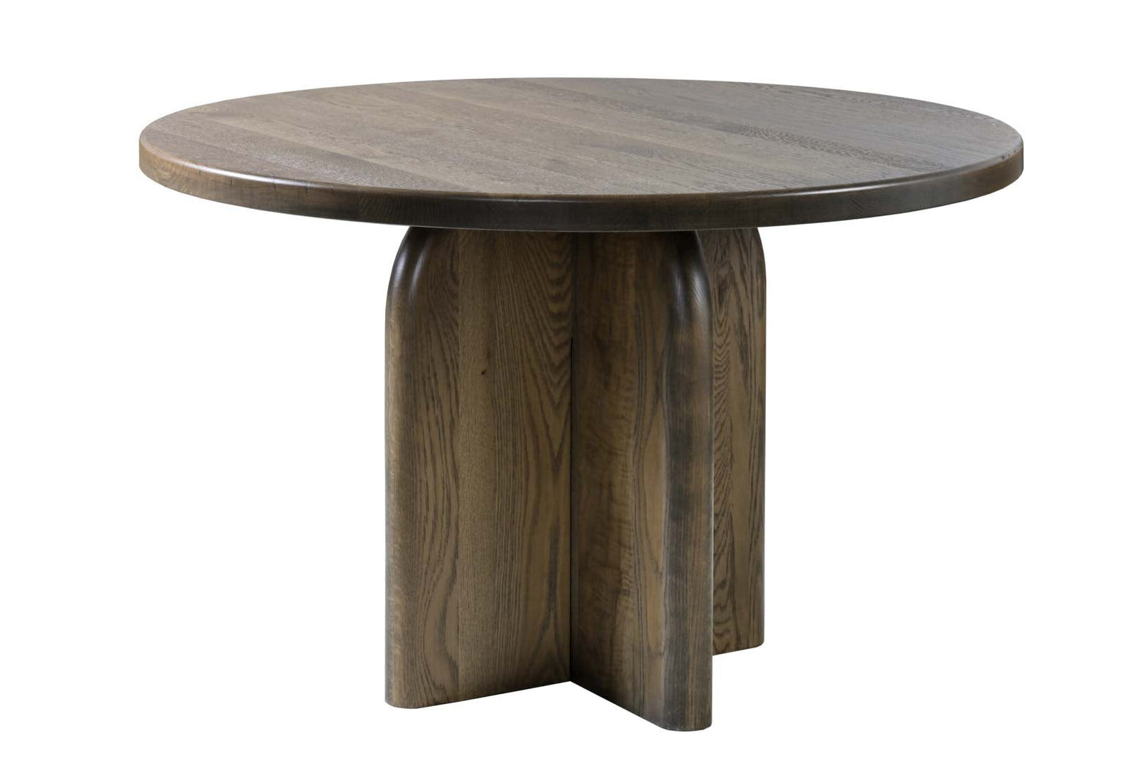 Round pedestal dining table in weathered oak with a sculptural column base, cream chairs and a bowl of lemons