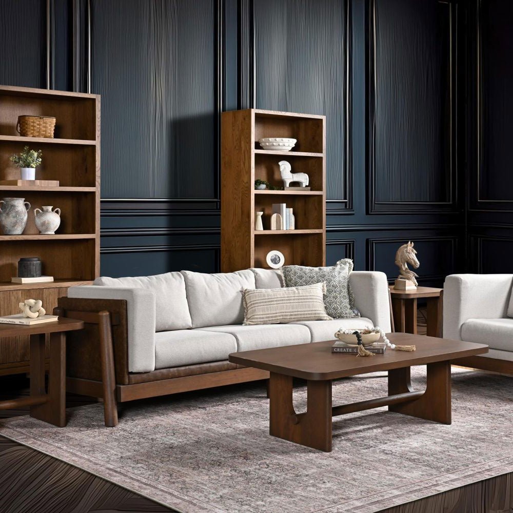 Mid century modern sofa with white cushions and a walnut wood frame in a navy paneled living room with bookcases