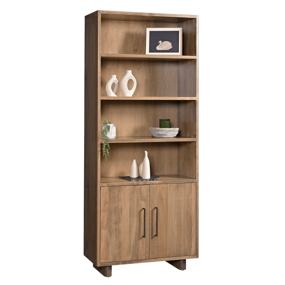 Tall solid wood bookcase with four open shelves and a two door lower cabinet with black bar pulls, styled with decor