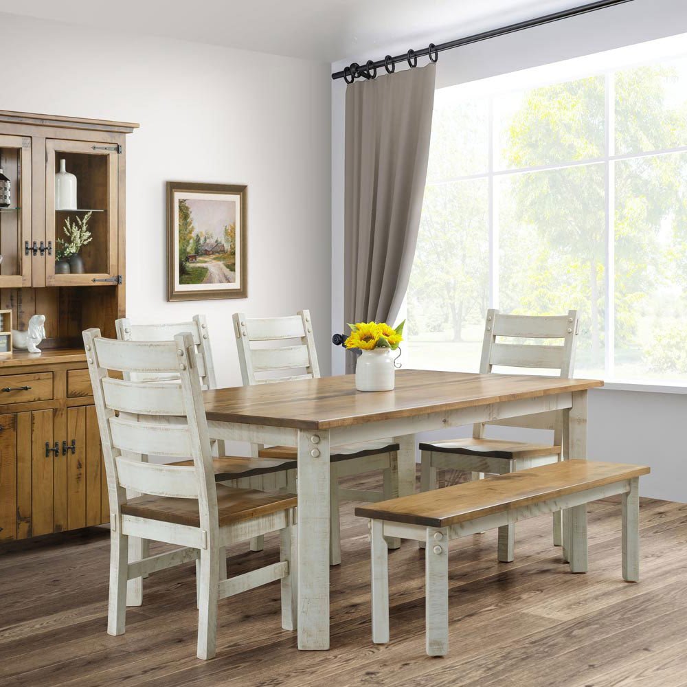 White washed rustic dining set with a stained top, ladder back chairs and a bench beside a pine hutch