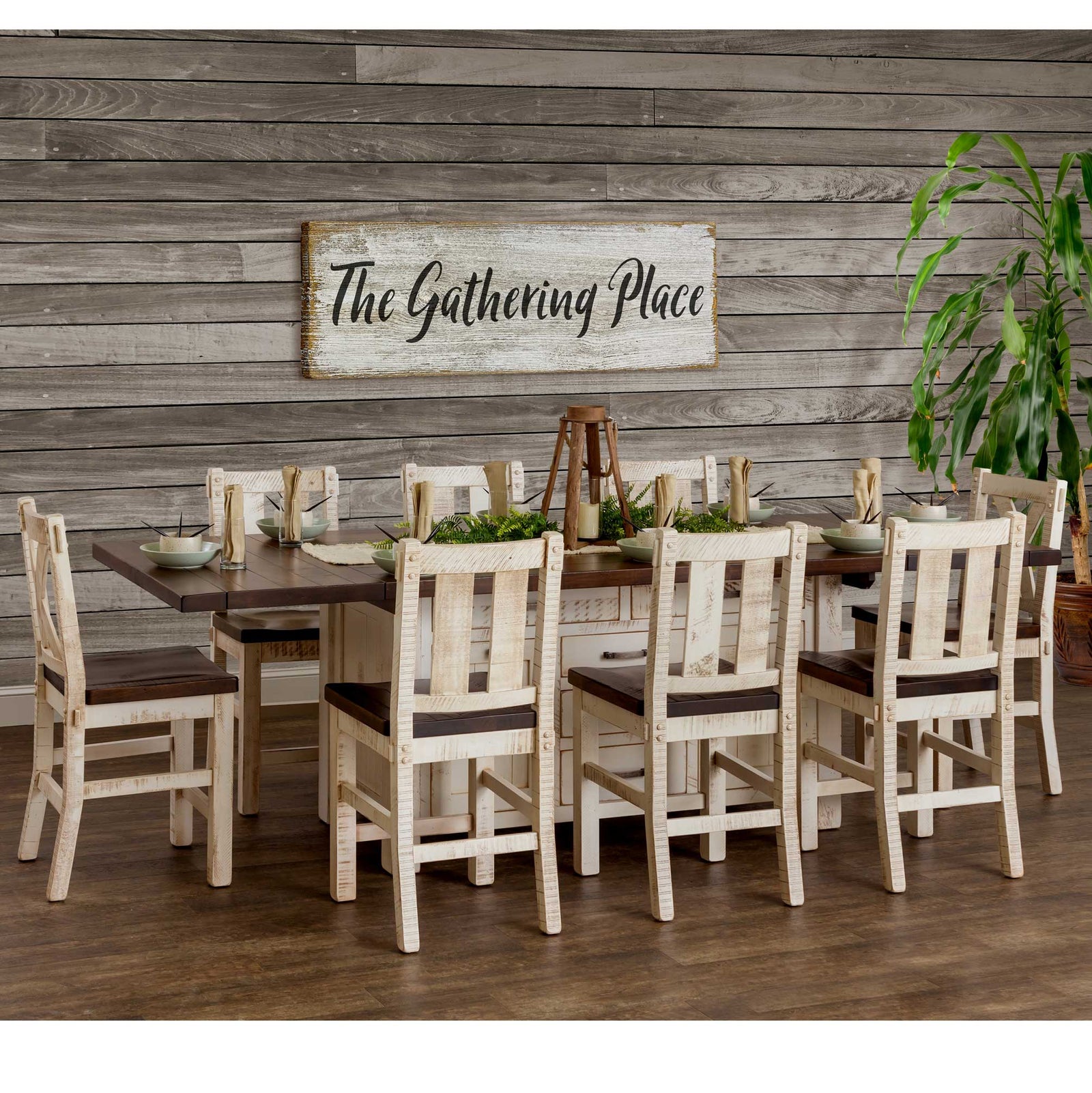 Long white kitchen island set for a crowd with eight rustic white bar chairs under a Gathering Place sign