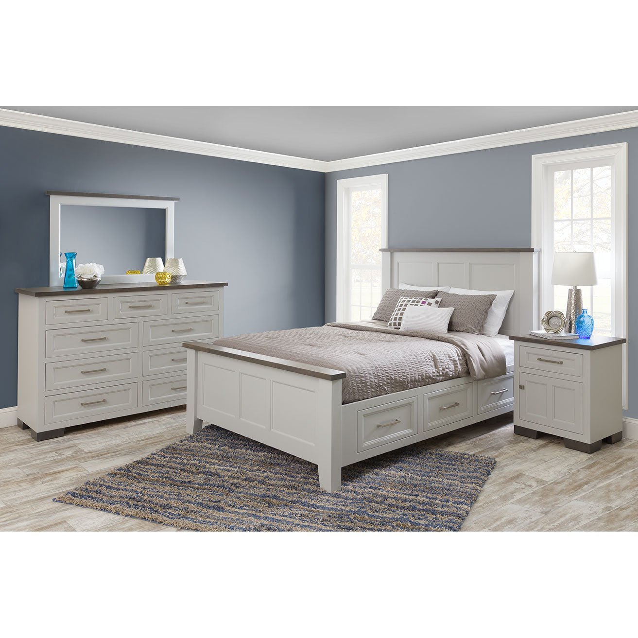 White bedroom set with storage bed, gray topped dresser and mirror and nightstand in a blue gray room