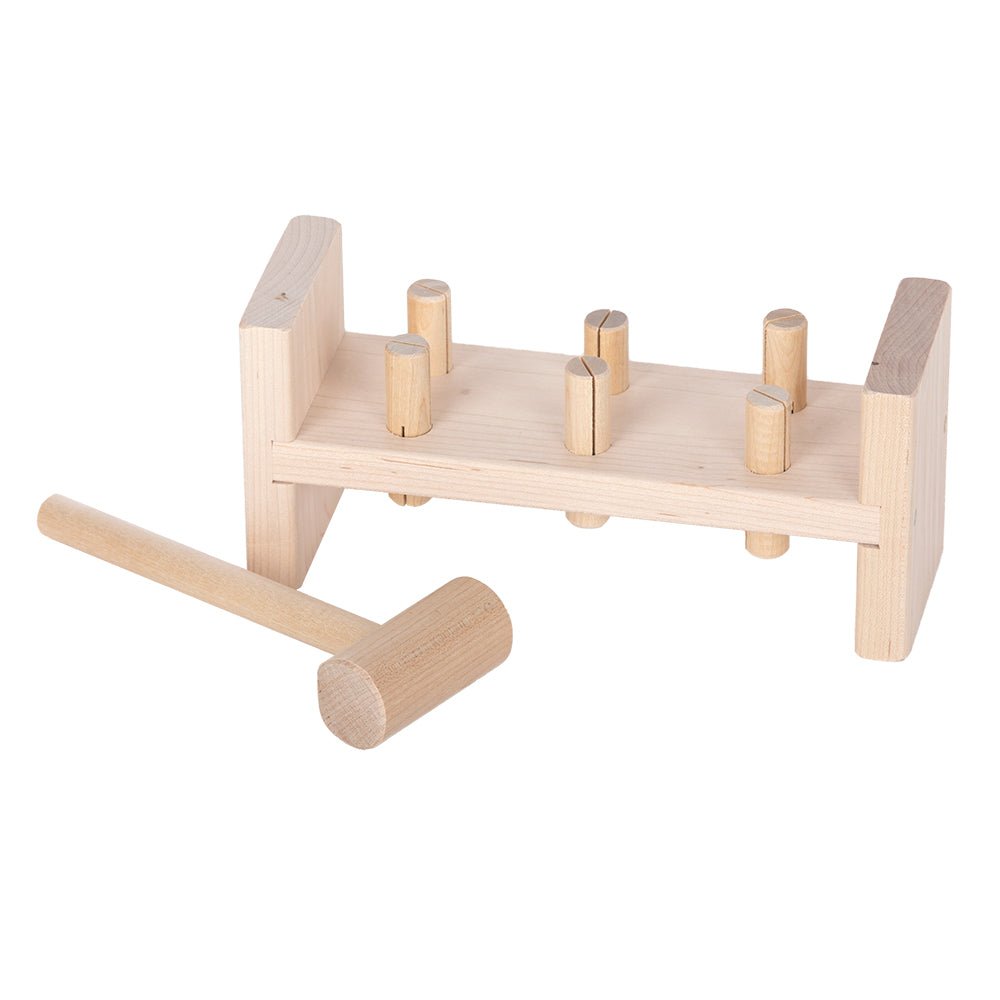 Wooden toy work bench in natural maple with six round pegs to pound and a matching wooden mallet lying beside it