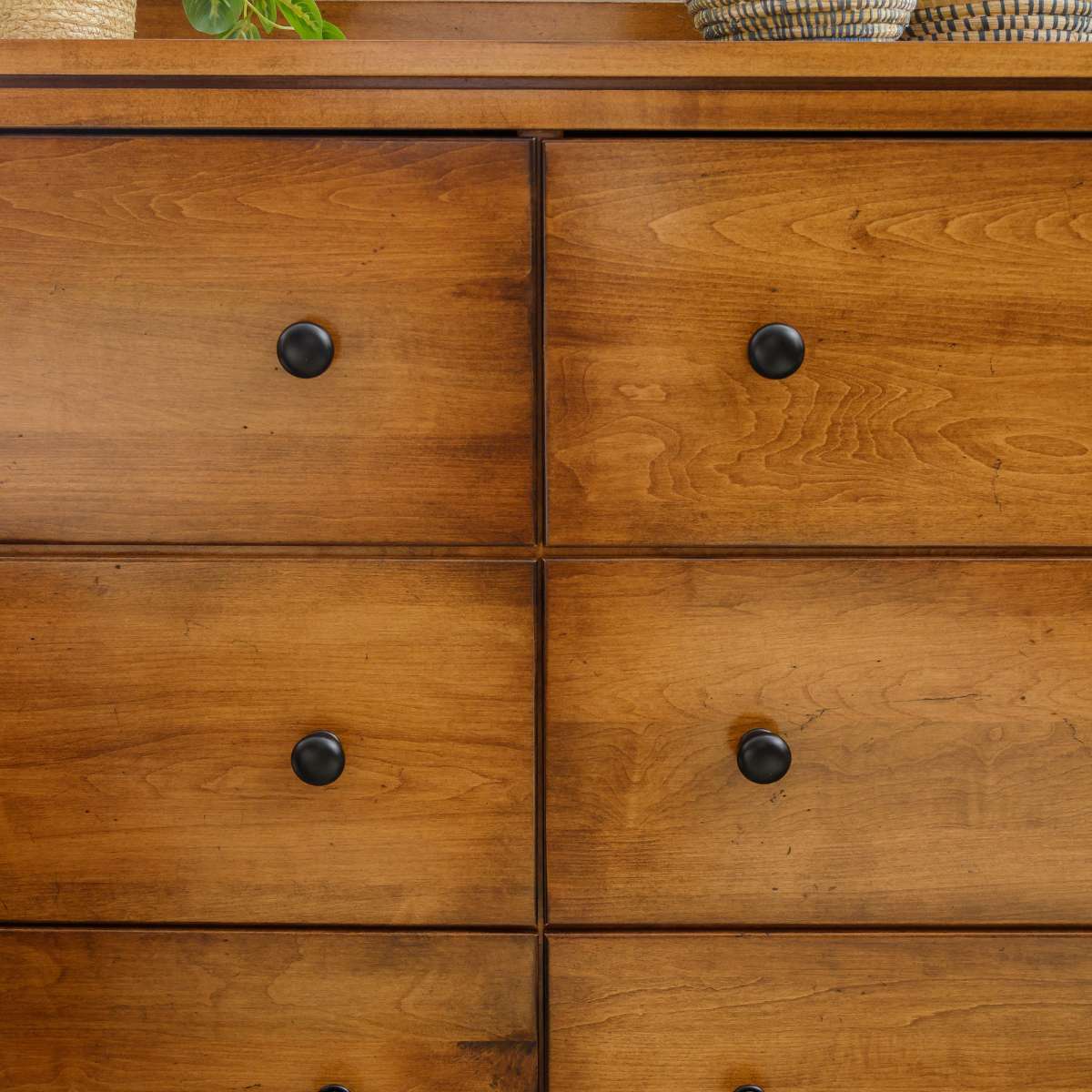 Detail of smooth maple drawer fronts in two columns with small round black knobs and thin reveals
