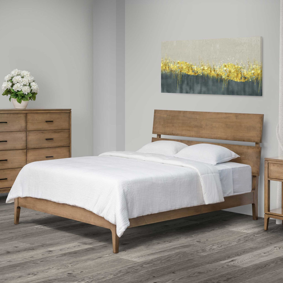Mid century sleigh bed in light driftwood-toned wood with an angled two-panel headboard and white bedding