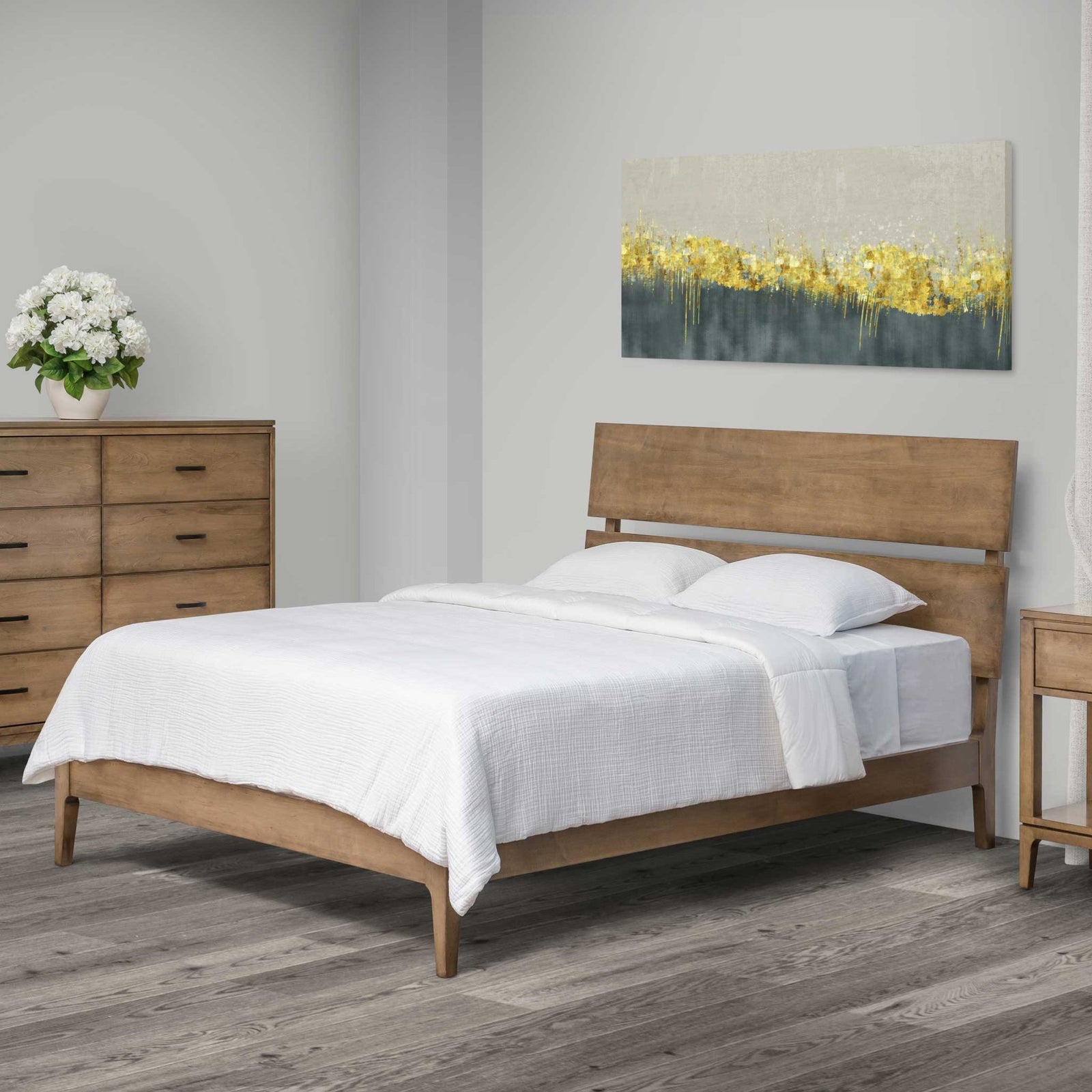 Mid century sleigh bed in light driftwood-toned wood with an angled two-panel headboard and white bedding