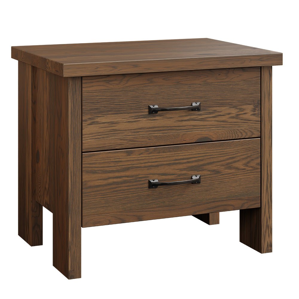 Two drawer oak nightstand with black bar pulls and a table lamp, placed beside a slatted headboard bed