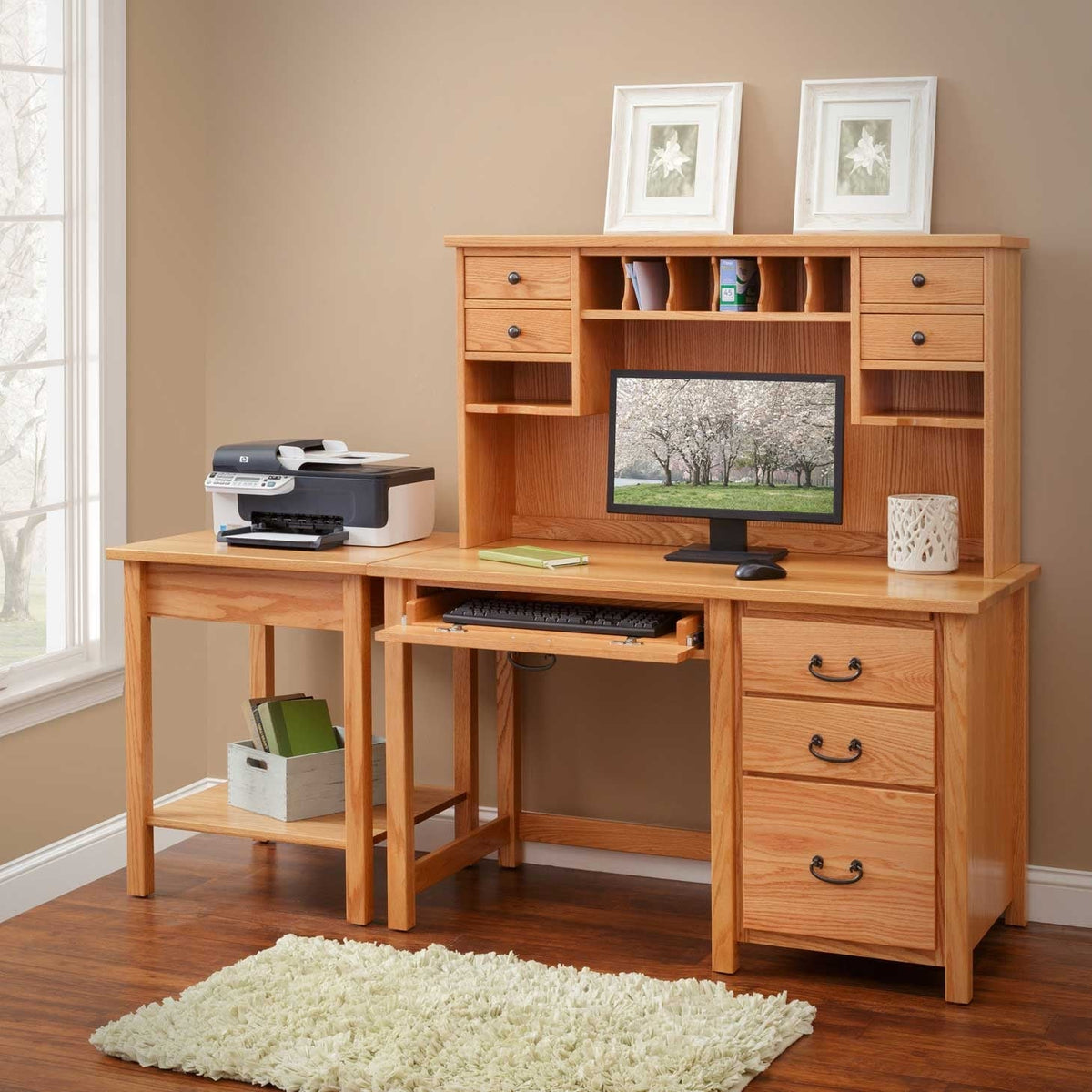Oak single pedestal desk with a low hutch, letter slots, keyboard tray, printer and monitor in a sunny office