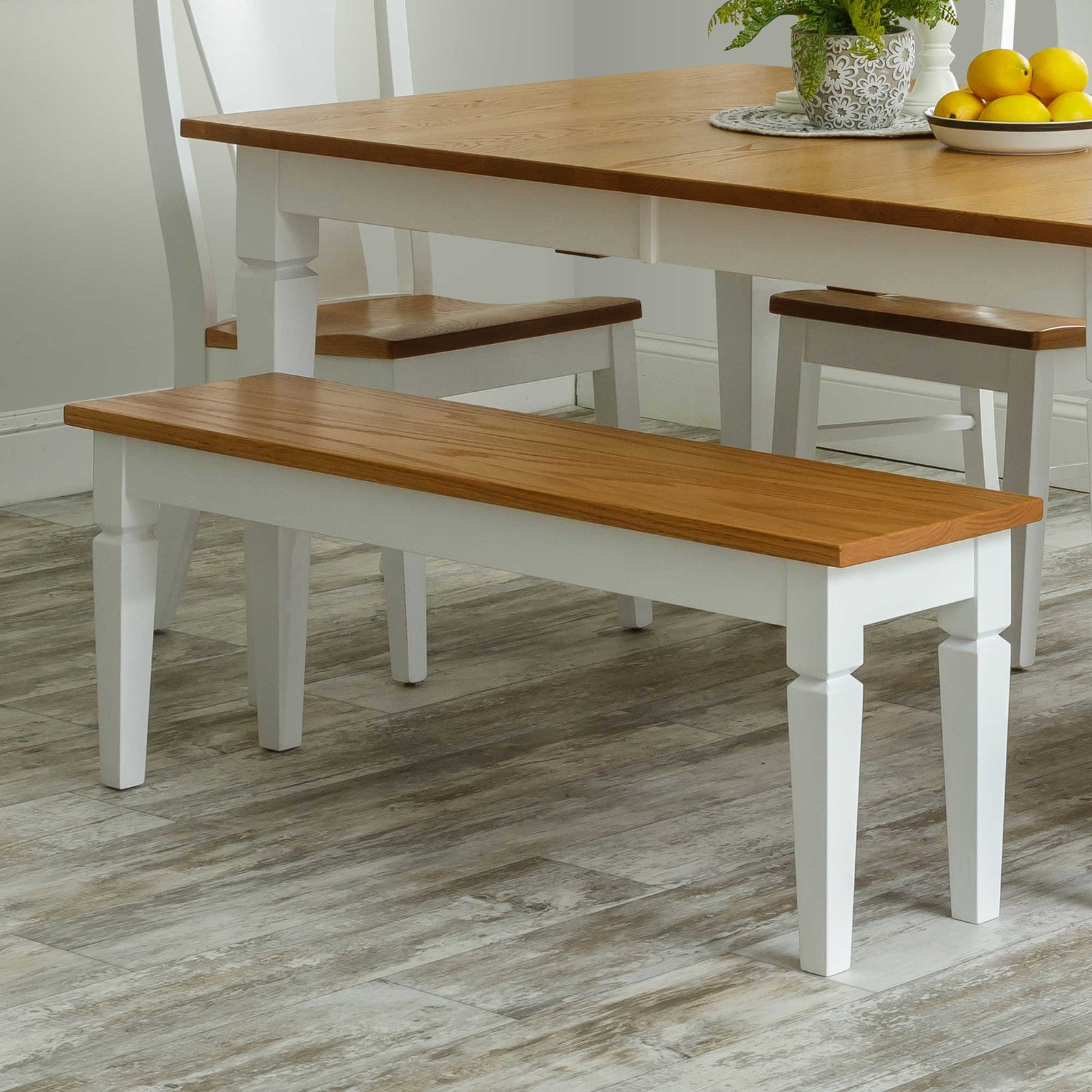 Two-tone dining bench with a natural oak seat and white painted turned legs beside a matching farmhouse table
