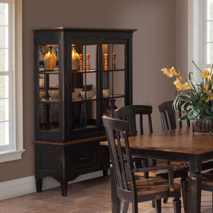 Distressed black china curio cabinet with lighted glass sliding doors, oak top and mirrored back in a dining room