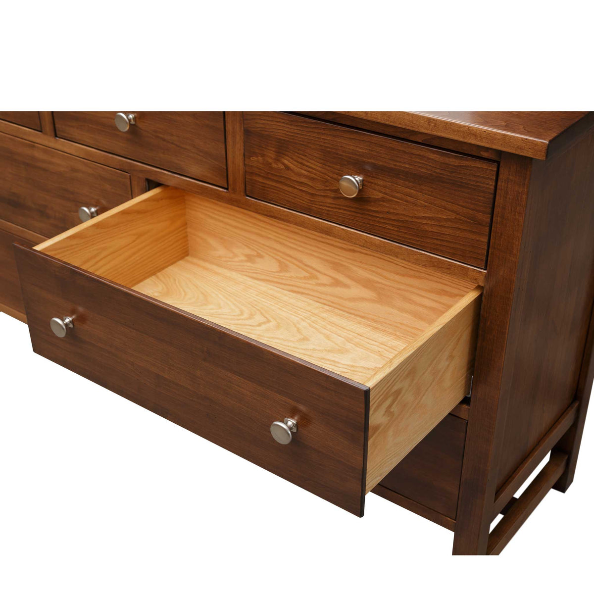 Open drawer with a natural maple dovetailed box in the brown seven-drawer dresser under nickel knobs
