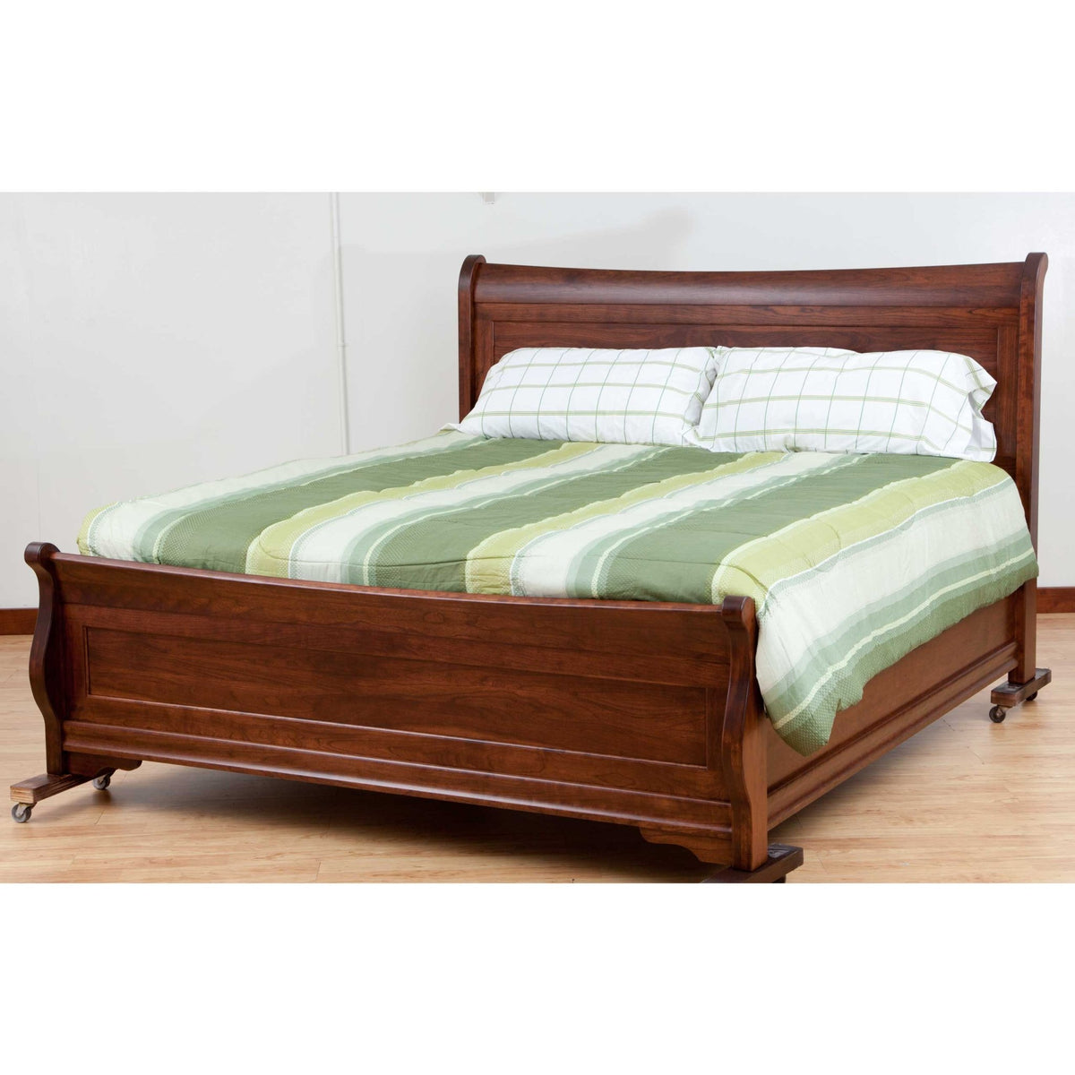 Solid cherry sleigh bed with scrolled headboard, paneled footboard and bracket feet, striped green bedding