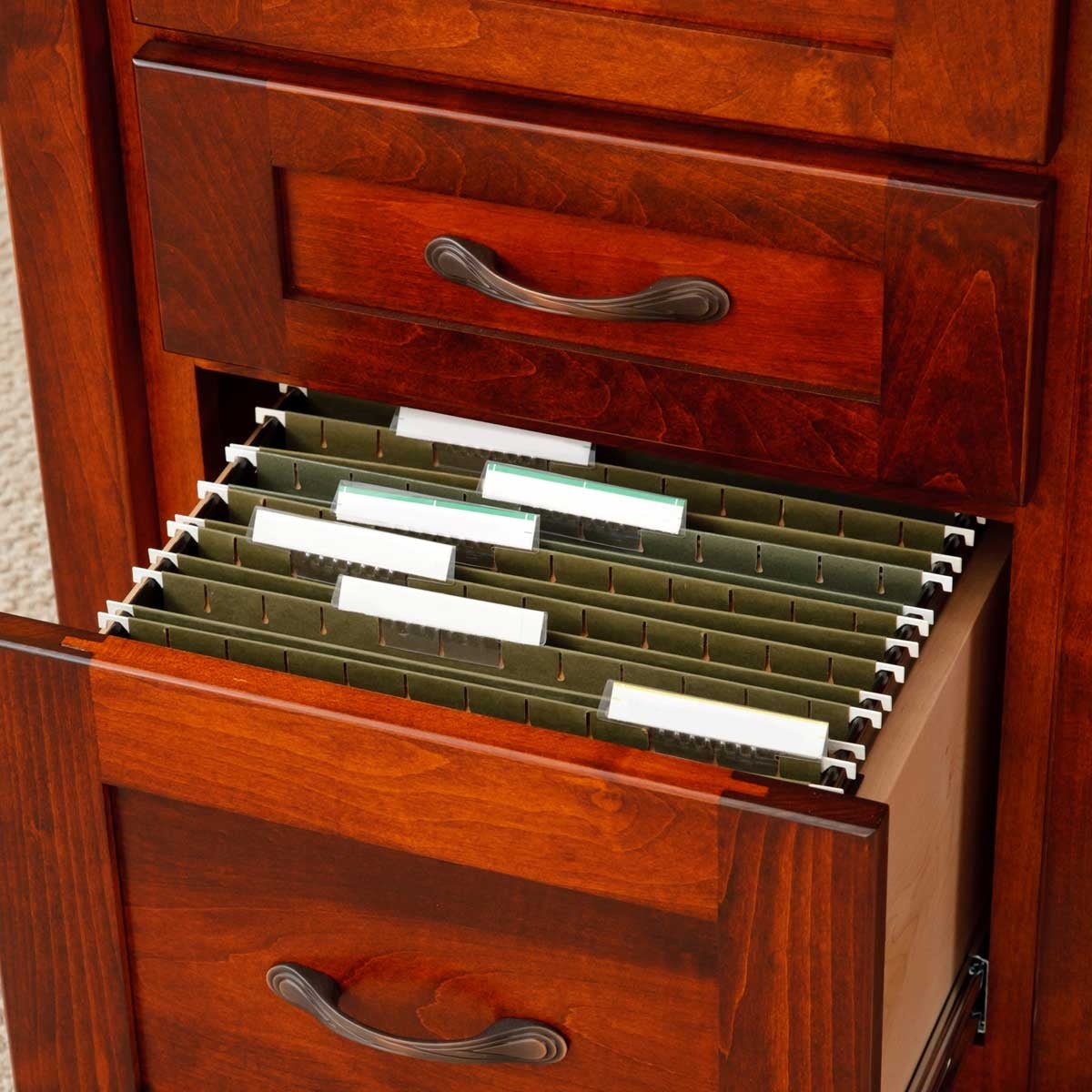 Hanging file storage inside an open lower drawer of a cherry desk pedestal, with paneled drawer fronts and dark pulls