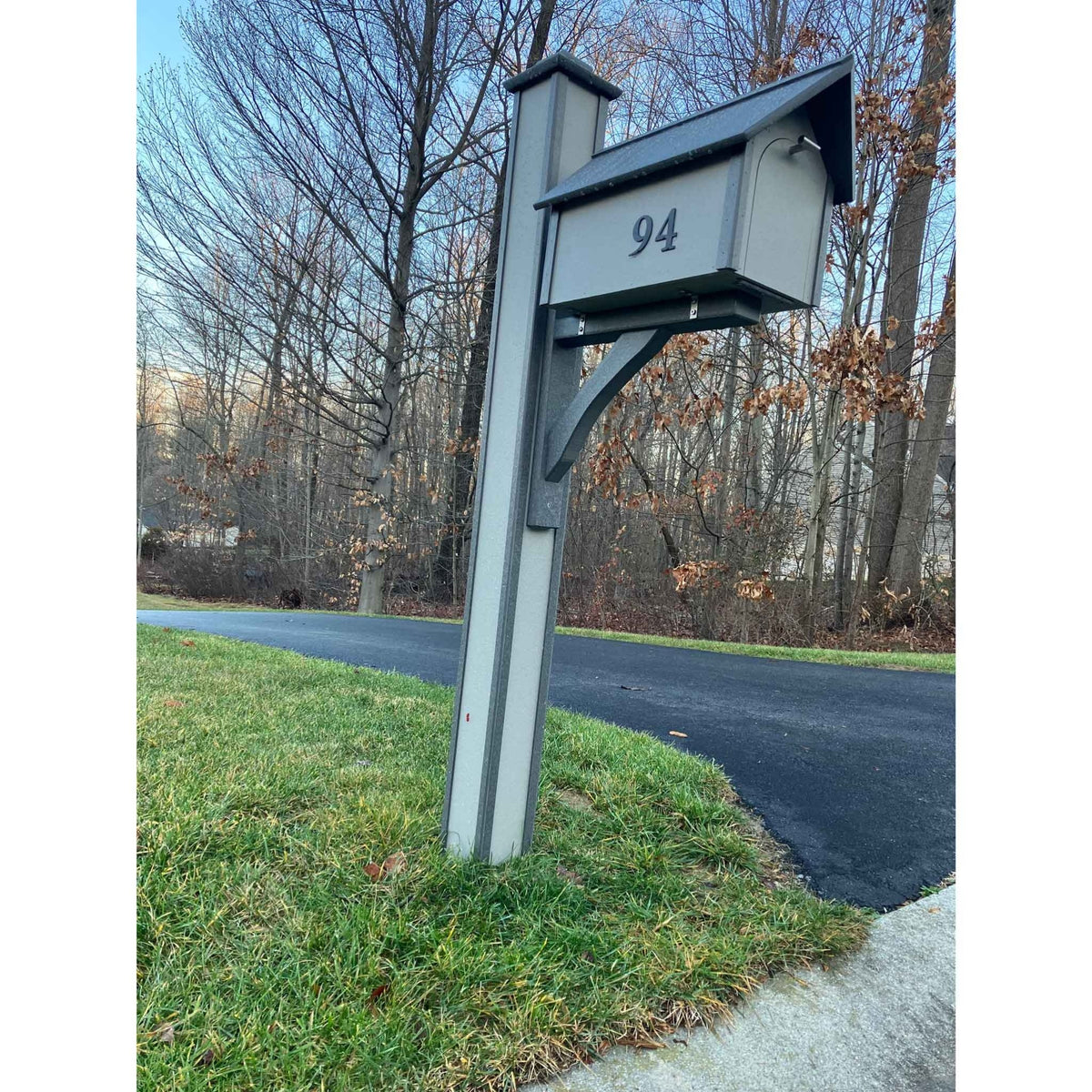 Gray poly mailbox post sleeve with angled brace and matching mailbox marked 94 at a driveway
