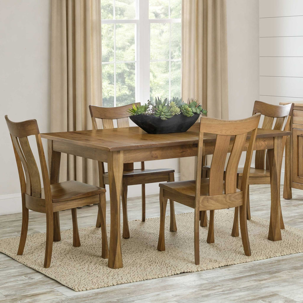 Rectangular dining table in a light natural finish with sculpted tapered legs and four matching wood chairs