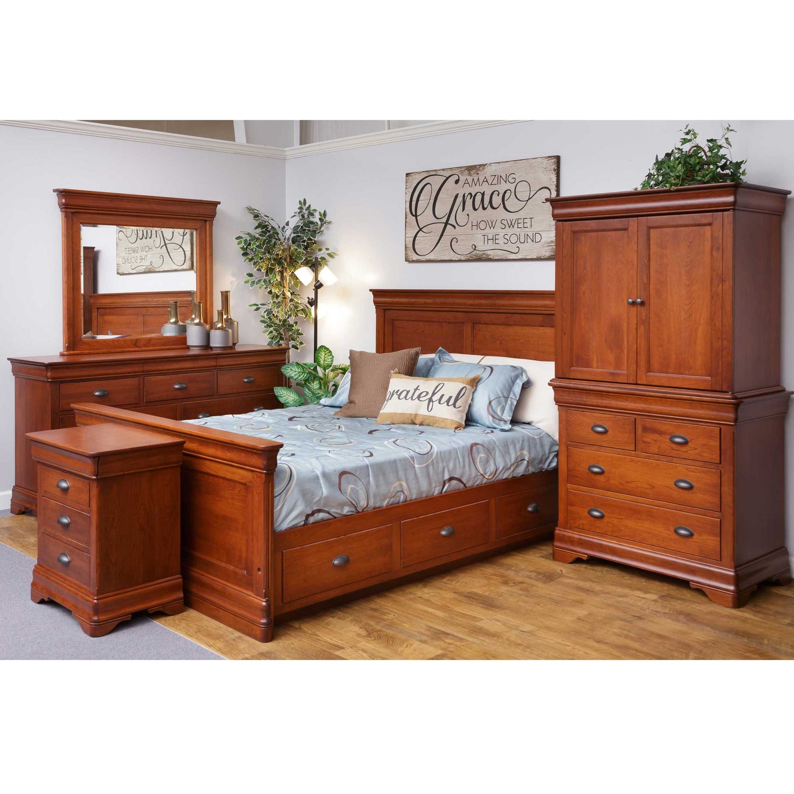 Cherry bedroom suite in a showroom with a storage sleigh bed, nightstand, dresser with mirror and armoire