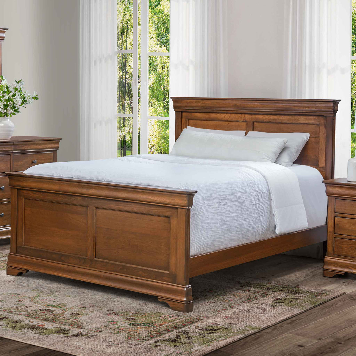 Cherry panel bed with a crown-topped headboard and raised panel footboard, made up with white bedding by a window