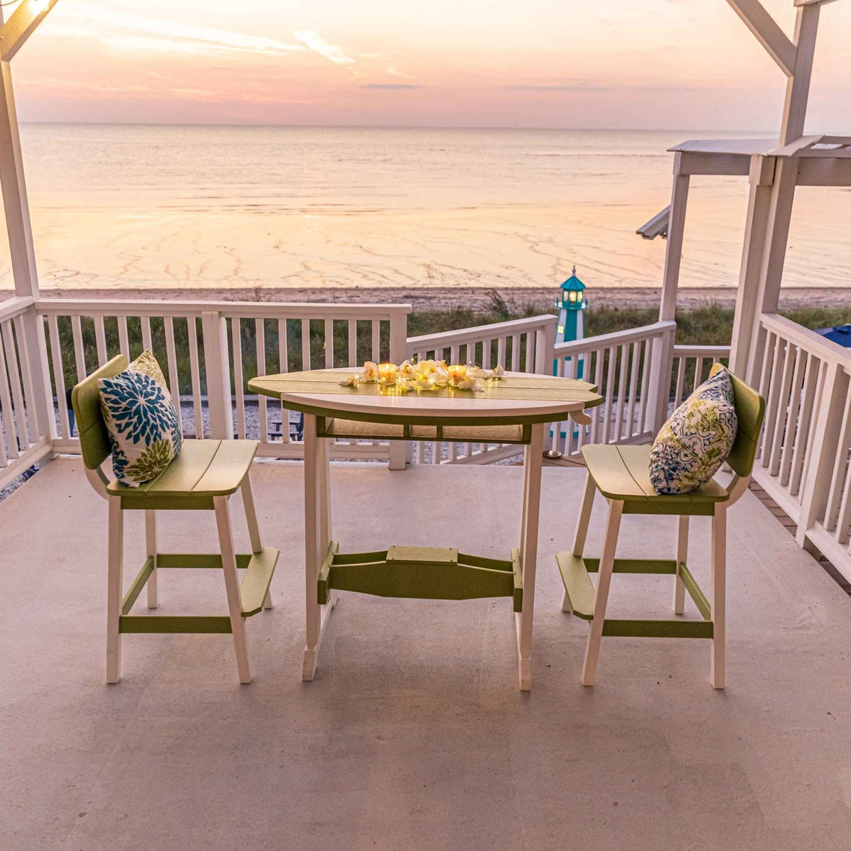 Lime green and white surfboard shaped counter table with two bar chairs on an oceanfront porch at sunset