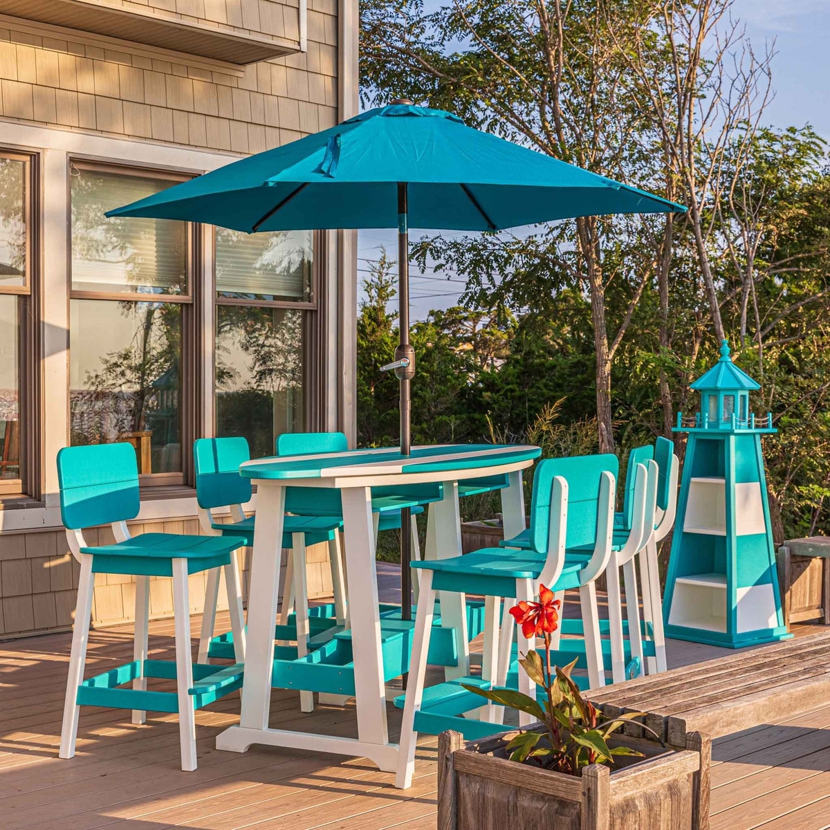 Aruba blue and white surfboard shaped bar table with six bar chairs, teal umbrella and lighthouse on a deck
