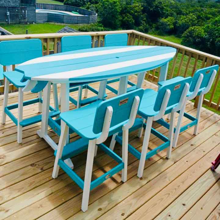 Overhead view of the turquoise and white surfboard bar table with six chairs on a wood deck