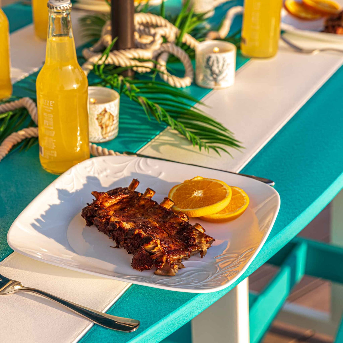 Detail of the surfboard shaped poly table top in turquoise and white with a plated dinner