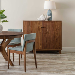 Walnut mid century server cabinet with two flat panel doors beside a dining table and green chairs