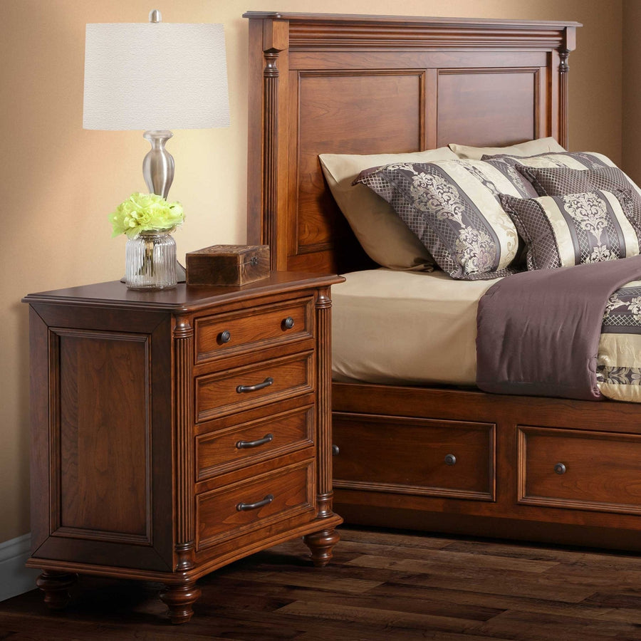 Warm cherry Milano nightstand with four drawers and reeded corner posts staged next to a paneled headboard and storage bed