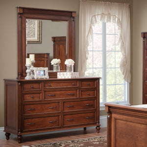 Cherry nine-drawer dresser with a tall vertical beveled mirror, styled with candles and flowers by a curtained window