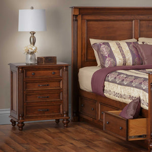 Cherry Milano four-drawer nightstand with fluted columns, turned bun feet and dark bronze pulls beside a paneled storage bed
