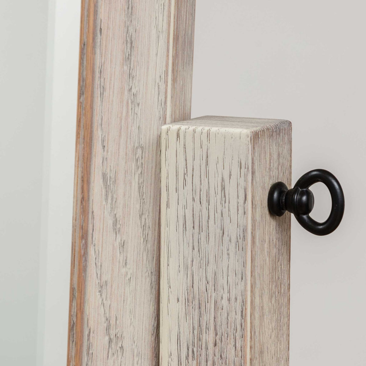 Detail of the black ring-style pivot knob on the whitewashed cheval mirror's side post