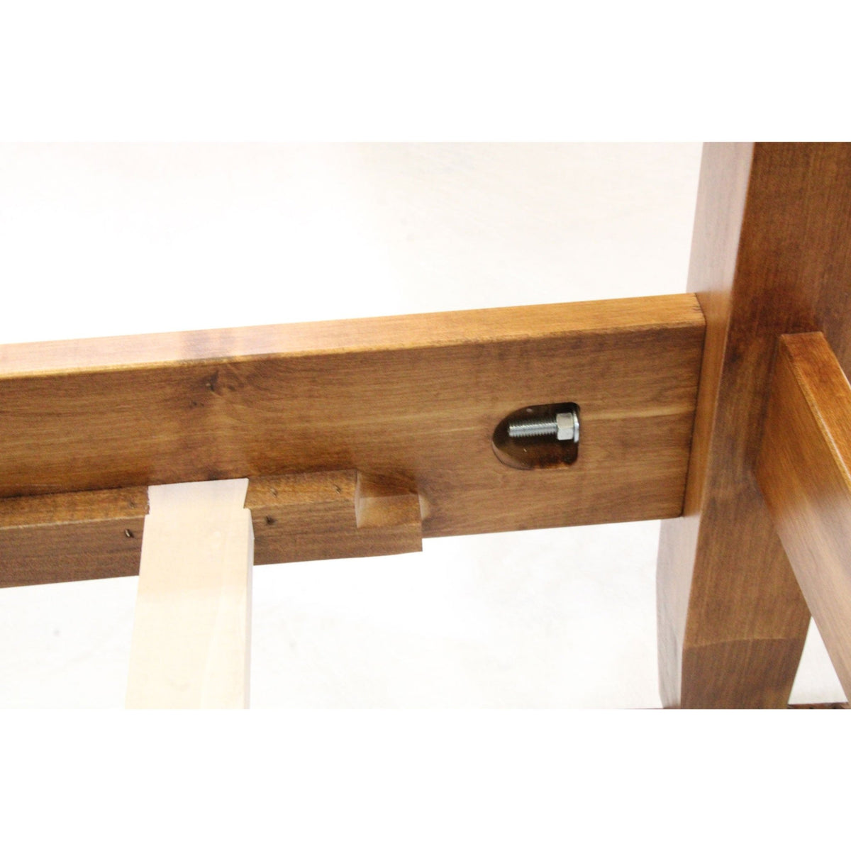 Close-up of a bed rail hex bolt fastener with maple slat resting on the wood support cleat