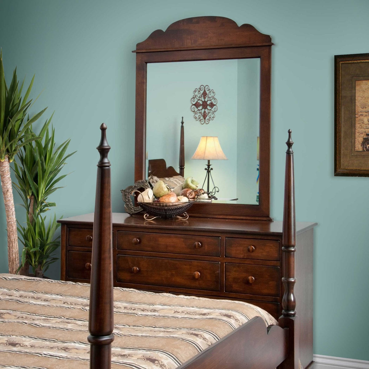 Scroll-top mirror and dresser styled in a bedroom beside a poster bed