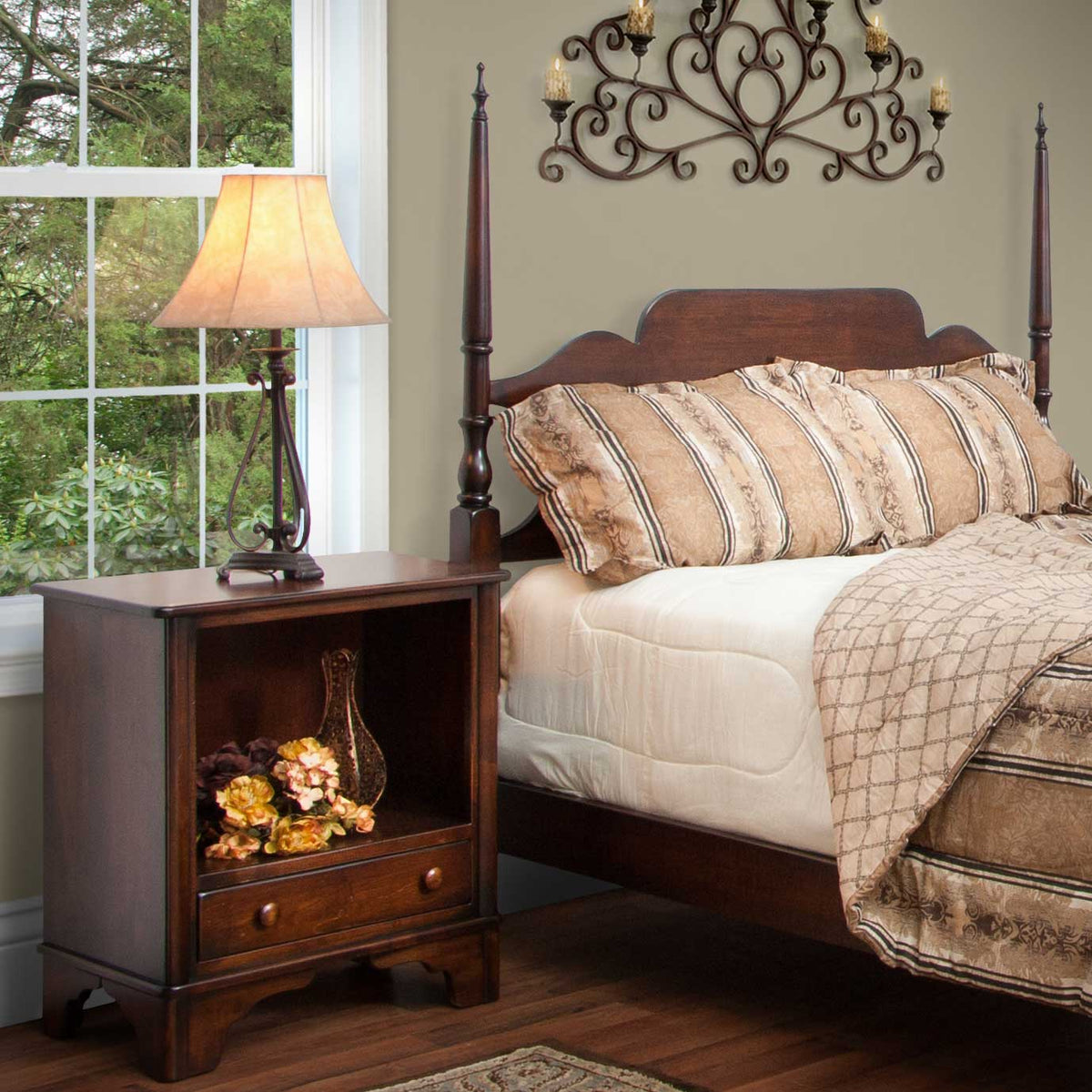 Cherry library night table with an open shelf above one drawer, beside a poster bed and lamp by a window