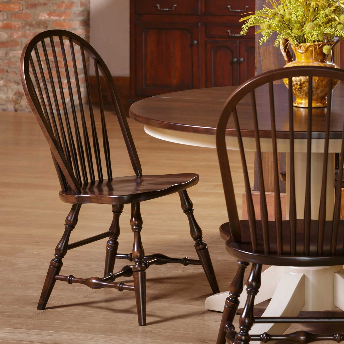 Dark Windsor bow back side chairs with sculpted seats at a round table with a cream painted pedestal