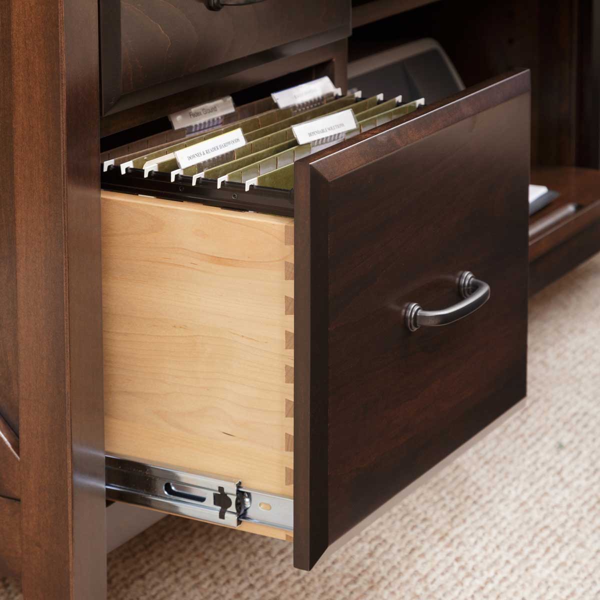 File drawer pulled open on the walnut desk showing labeled hanging folders and dovetailed maple sides