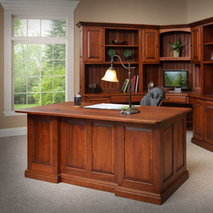 Back of the cherry executive desk showing finished raised panels, two wire grommets and a stepped base