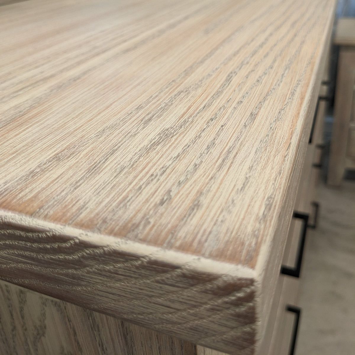 Close-up of the whitewashed oak dresser top edge, showing cerused grain and a rounded corner profile