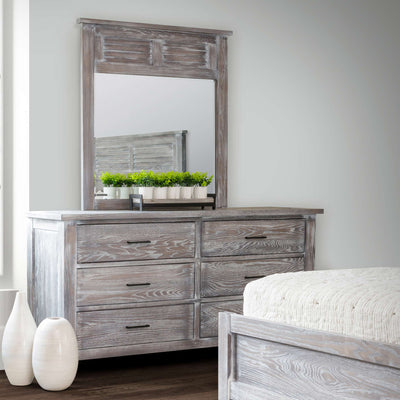 Weathered gray six drawer dresser with matching louvered mirror styled in a bedroom with white vases