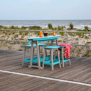 Turquoise poly surfboard shaped counter height table with gray legs and stools on an oceanfront boardwalk